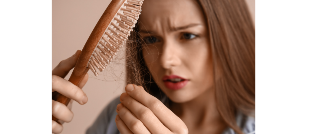 Woman brushing her hair with visible strands coming out of the brush, showing increased daily shedding
